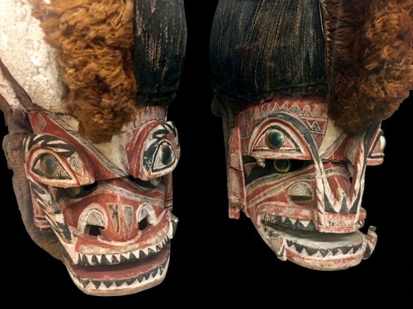 Masques africains en bois sculpté, montrant des visages anthropomorphes avec des détails colorés et des yeux en pierre.